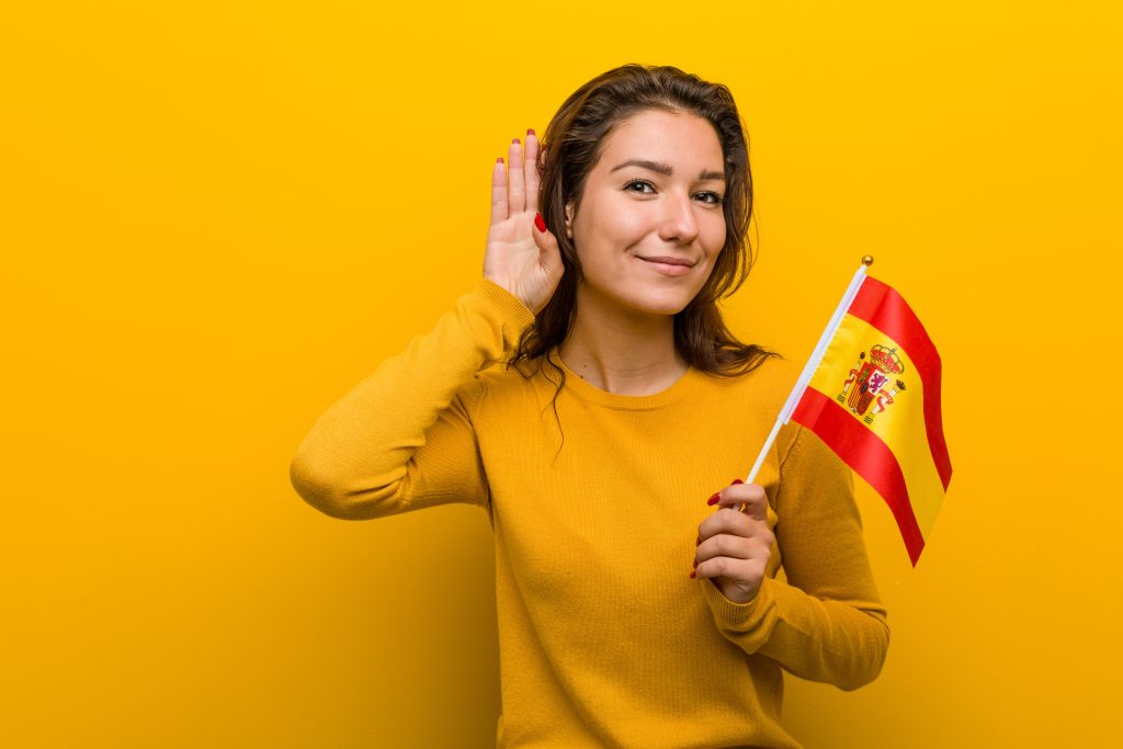 young woman holding Spanish flag. she learns Spanish
